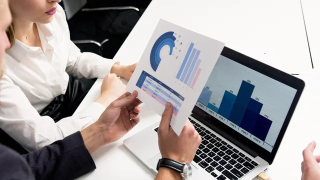 Business professionals discussing data charts and graphs in a modern office setting. Calculating cost per qualified lead