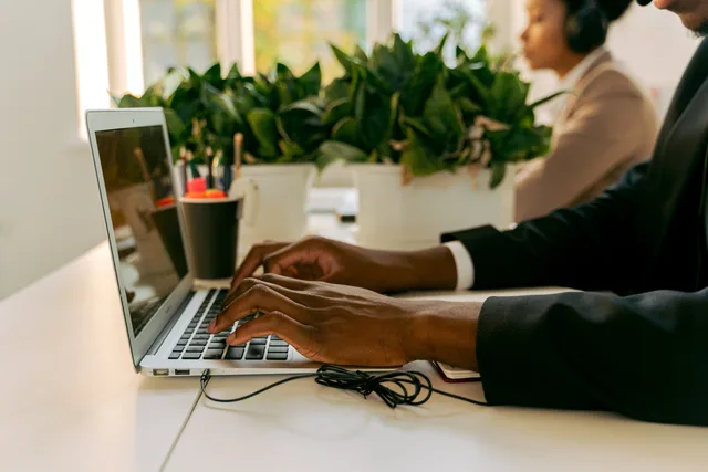 Business professional typing on a laptop in a modern office setting with natural light and plants. Connecting website enquiries with CRM outcomes