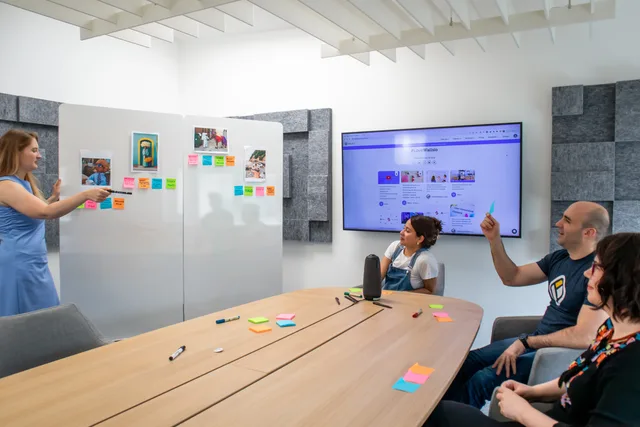 A group of coworkers engaged in a creative brainstorming session with colorful Post-it notes and a digital display. Lead generation experiments