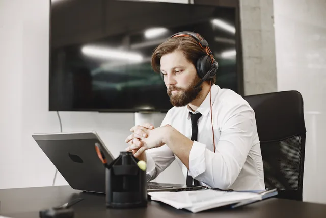 Focused professional man working remotely with headset in modern office setting. Separating lead generation from outbound prospecting
